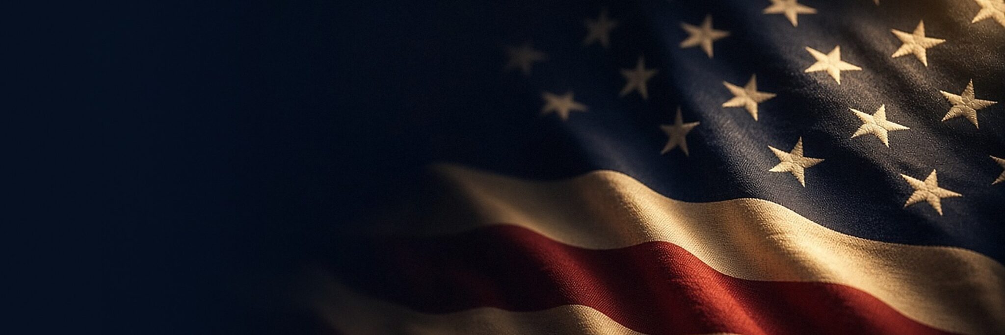 An American flag in deep navy shadow with a gold rim of light